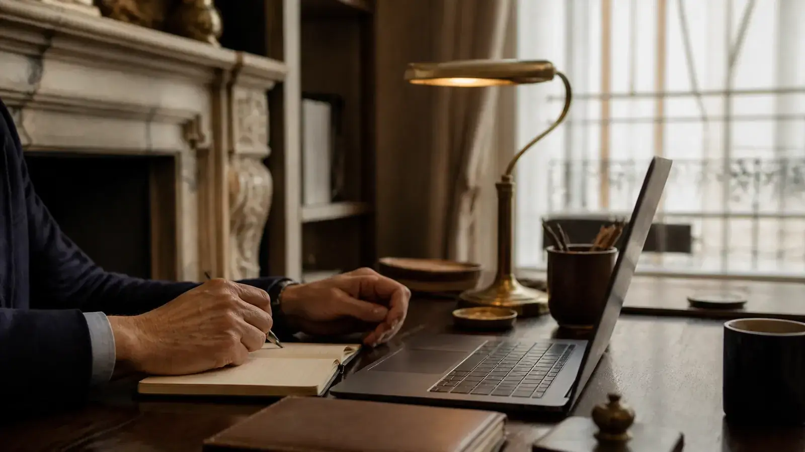 Close-up of a focused London home office desk session with laptop, notebook and secondary glazed sash window softly visible Close-up of a focused London home office desk session with laptop, notebook and secondary glazed sash window softly visible