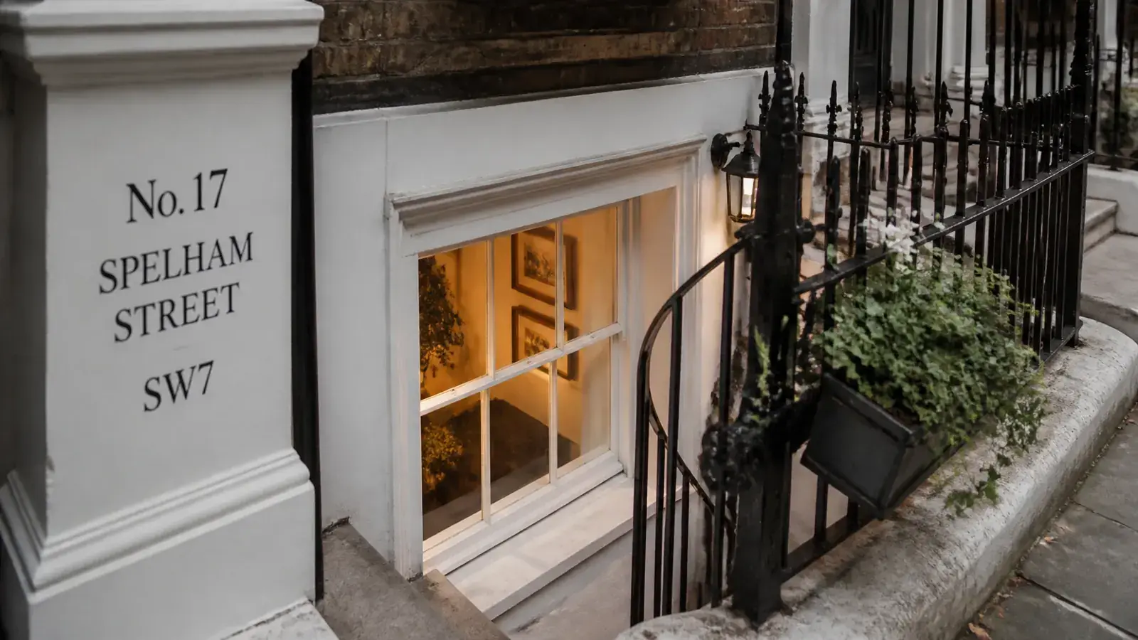 Exterior view looking down toward a London basement window reveal beneath a heritage façade