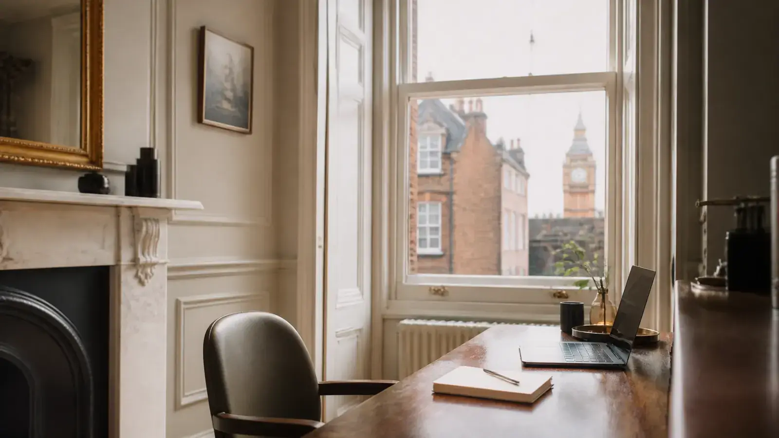 Stylish London home office desk beside a period sash window with discreet secondary glazing, laptop and notebook in view